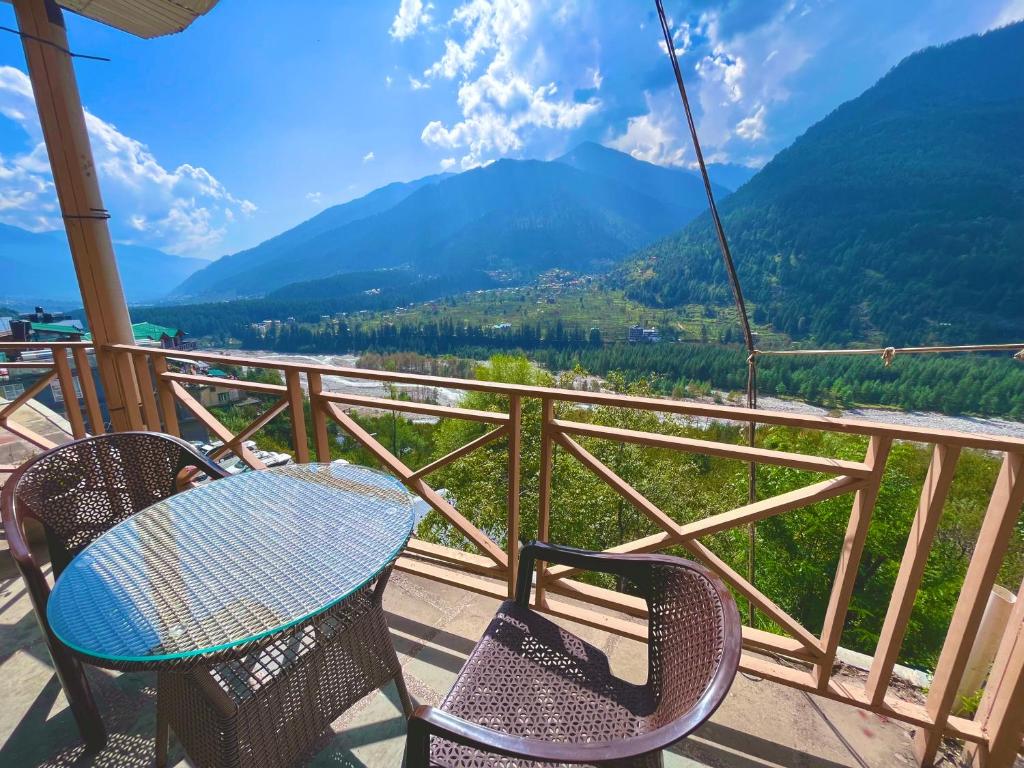 a table and chairs on a balcony with mountains at Valley of Gods, Vashisht Manali in Manāli