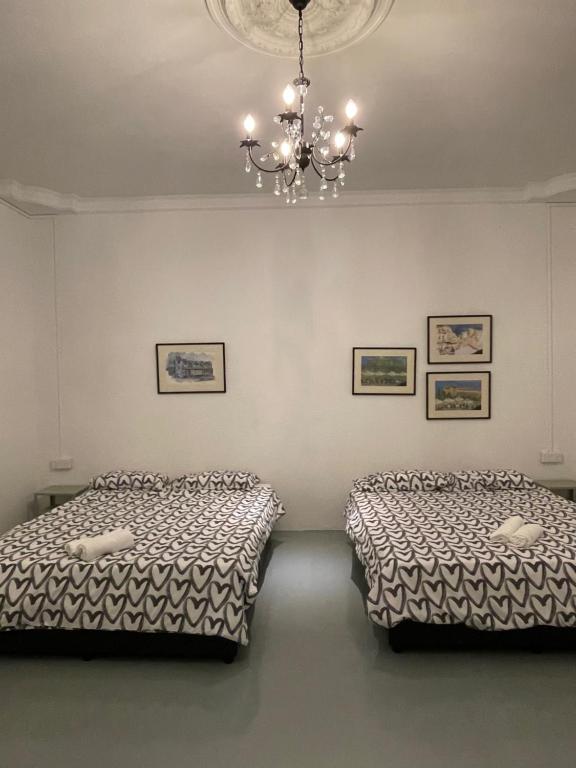 two beds in a room with a chandelier at Homestay "Feel at Home" Near A Famosa & Jonker Street for 4-7 people in Melaka