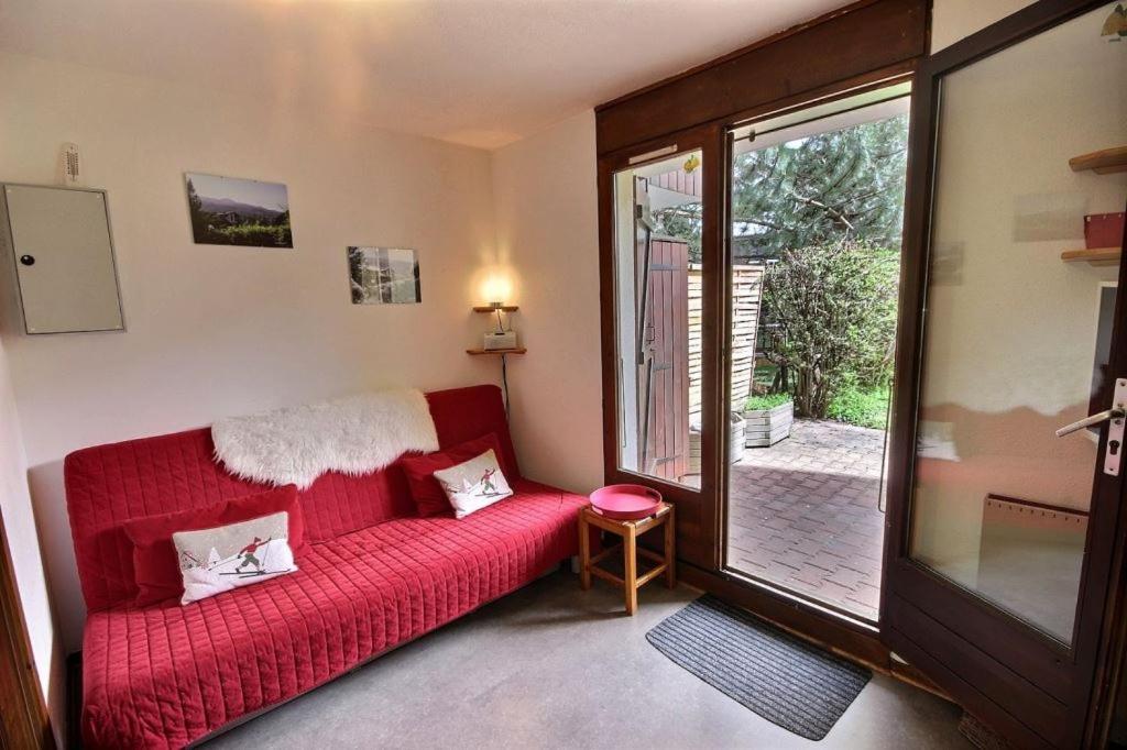 a living room with a red couch and a sliding glass door at les 3 marmottes les Glières in Bourg-Saint-Maurice
