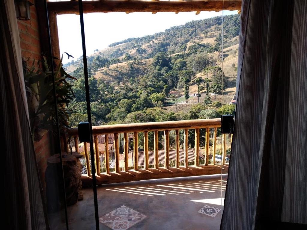 a room with a view of a mountain from a balcony at Chalé charmoso com vista p/ Montanha - Gonçalves in Paraisópolis
