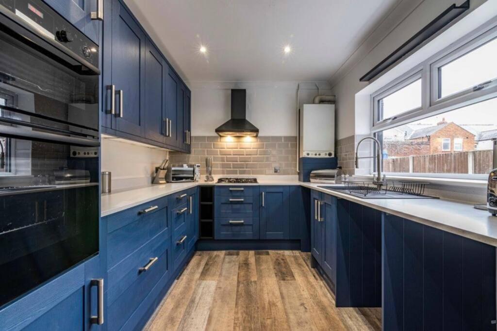 een keuken met blauwe kasten en een raam bij Westfield 3 Bed Characterful and Modern House FREE PARKING and private garden in Mansfield