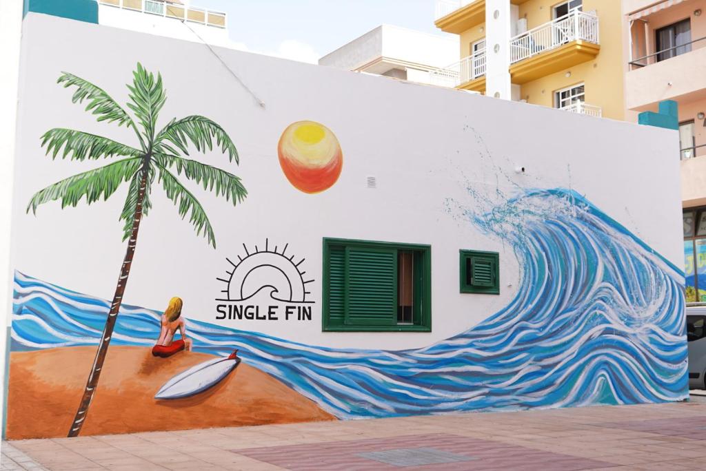 a mural of a palm tree on the side of a building at Single Fin Hostel in Arona