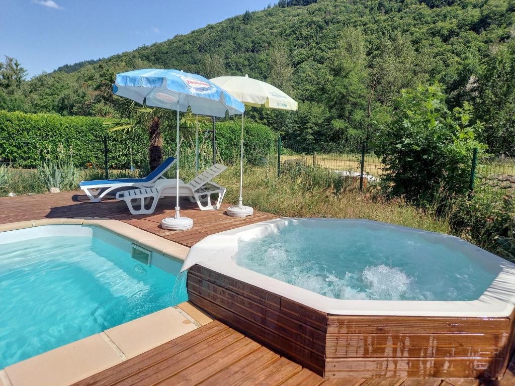 a swimming pool with an umbrella and a chair at Auberge de Barnas in Barnas