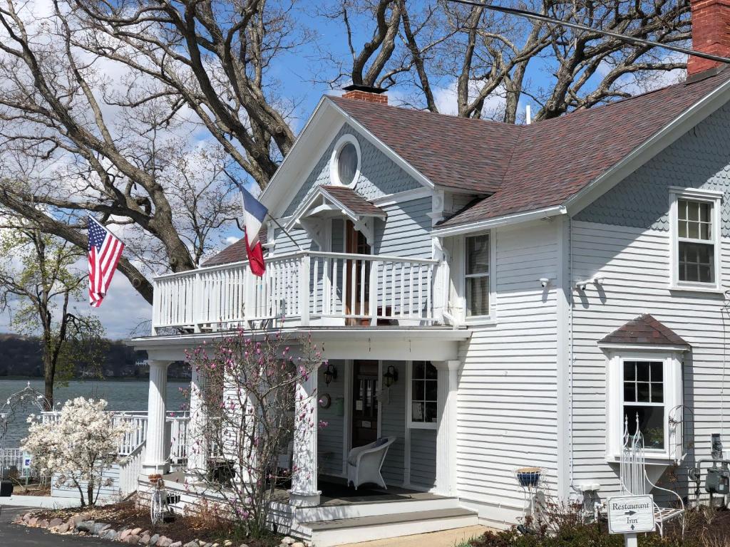 a white house with a balcony and an american flag at The French Country Inn in Lake Geneva