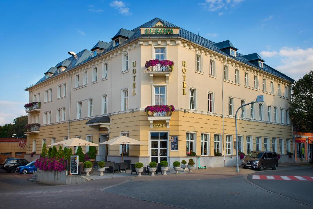 un grand bâtiment jaune avec des fleurs devant lui dans l'établissement Hotel Europa, à Poprad