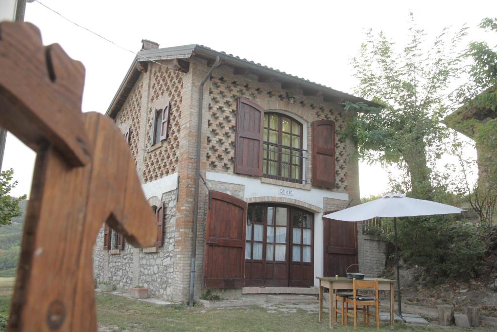 una casa con una mesa y una sombrilla delante de ella en CàMia, en Torrazza Coste