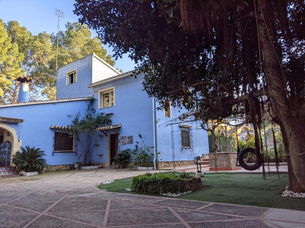 una casa azul con un árbol delante en Estudio Las Rotas en Dénia