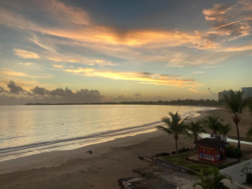 - une vue sur la plage bordée de palmiers au coucher du soleil dans l'établissement Amapola SeaSide Beach Front Apartment, à San Juan