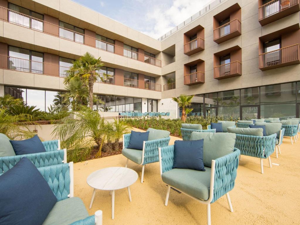 a row of chairs and tables in front of a building at Sines Sea View Business & Leisure Hotel in Sines