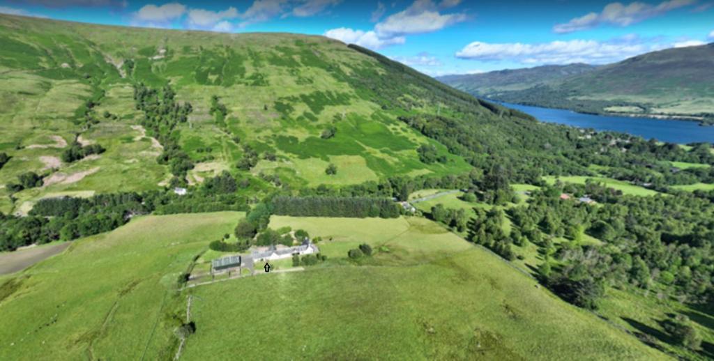 an aerial view of a green hill with a lake at Exclusive private estate cottage in Lochearnhead