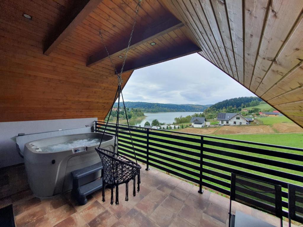 a balcony with a tub and a table and chairs at Domki Na Wzgórzu Słońce JACUZZI SAUNA ROWERY in Zawóz