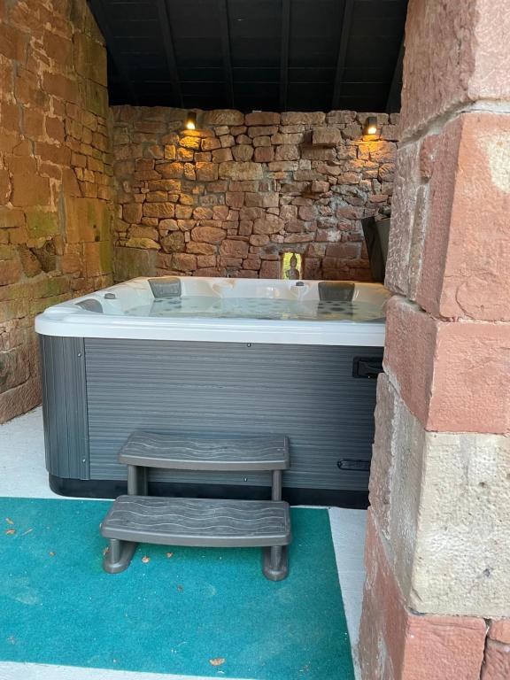 a bath tub with a bench next to a stone wall at Villa avec jaccuzi in Noailhac