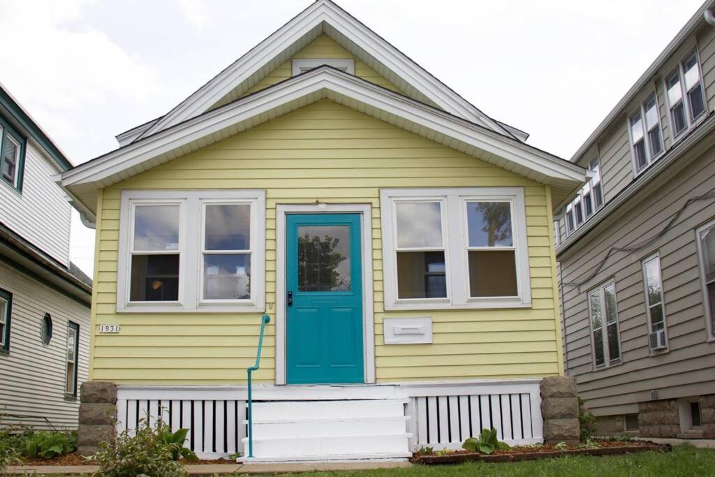 a yellow house with a blue door and windows at Cute yellow 2-BR bungalow w/free garage, free WiFi in Milwaukee