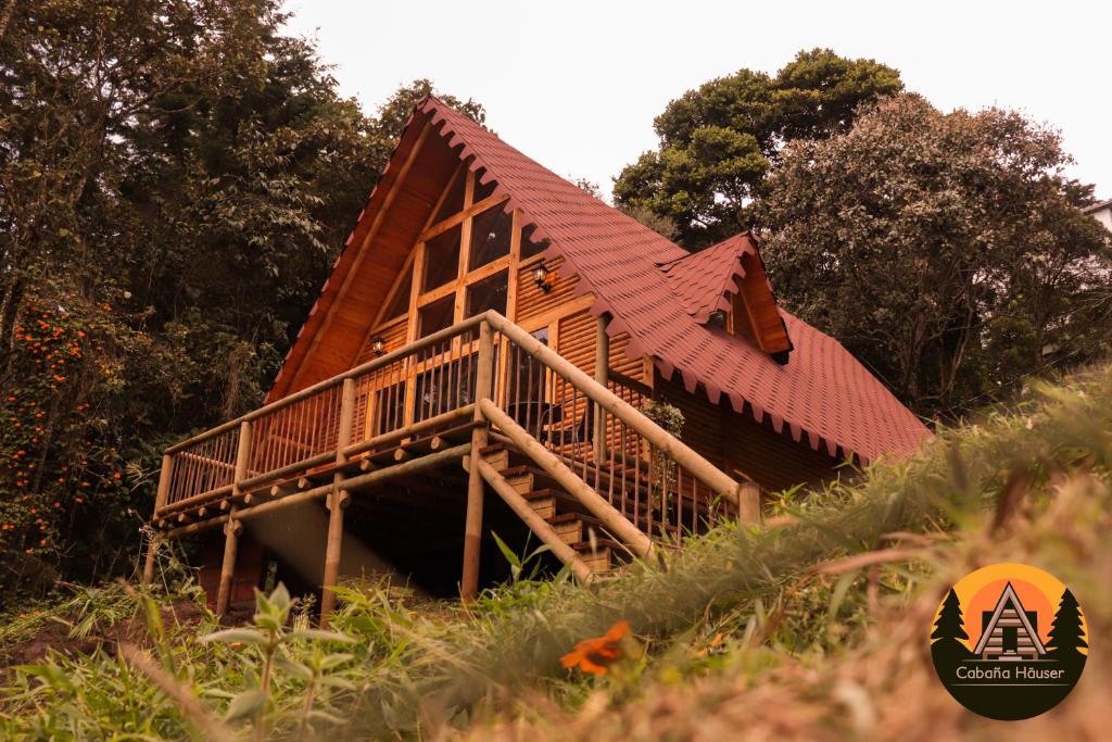 une cabane en rondins avec un toit rouge sur une colline dans l'établissement Espectacular Cabaña de lujo en Santa Elena, à Medellín