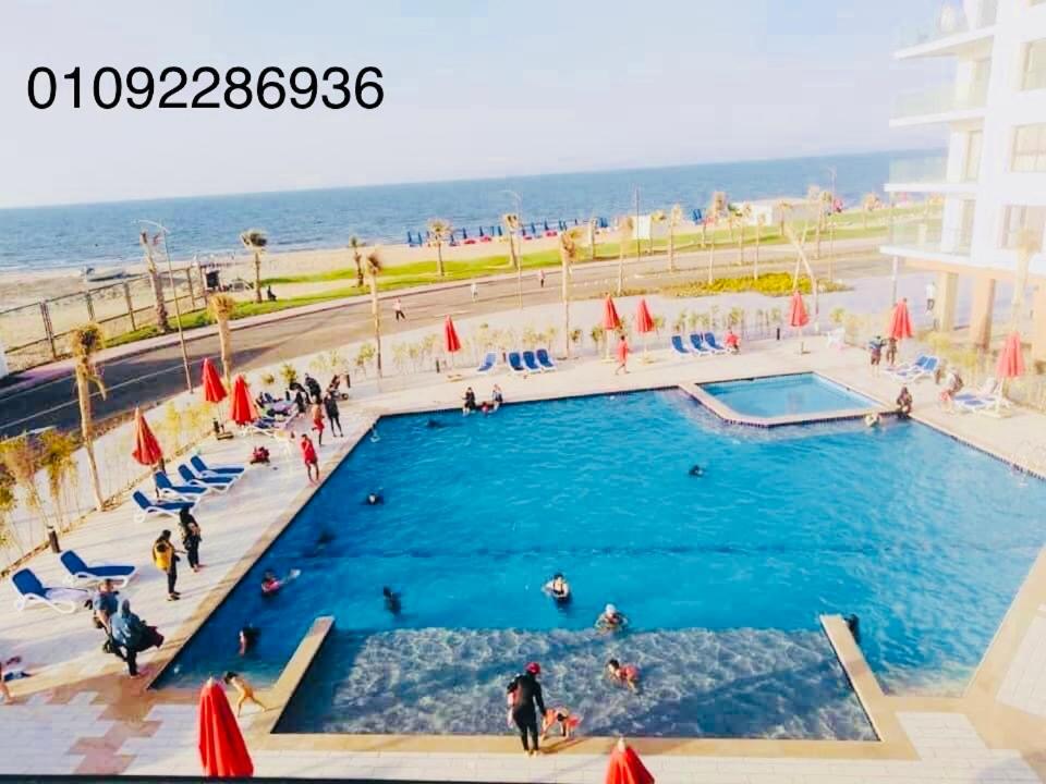 a large swimming pool next to the beach with people in it at بورتوسعيد Porto Said in Port Said
