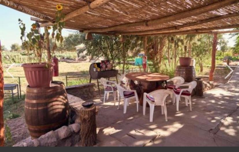 un patio con tavolo e sedie sotto un pergolato di Cabañas Pankara a San Pedro de Atacama