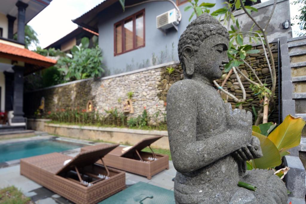 eine Statue einer Person, die neben einem Pool steht in der Unterkunft Jiwa's House in Ubud