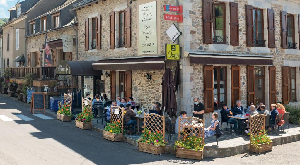 een groep mensen die aan tafels buiten een gebouw zitten bij Logis Hôtel-restaurant Les Coudercous in Saint-Chély-dʼAubrac