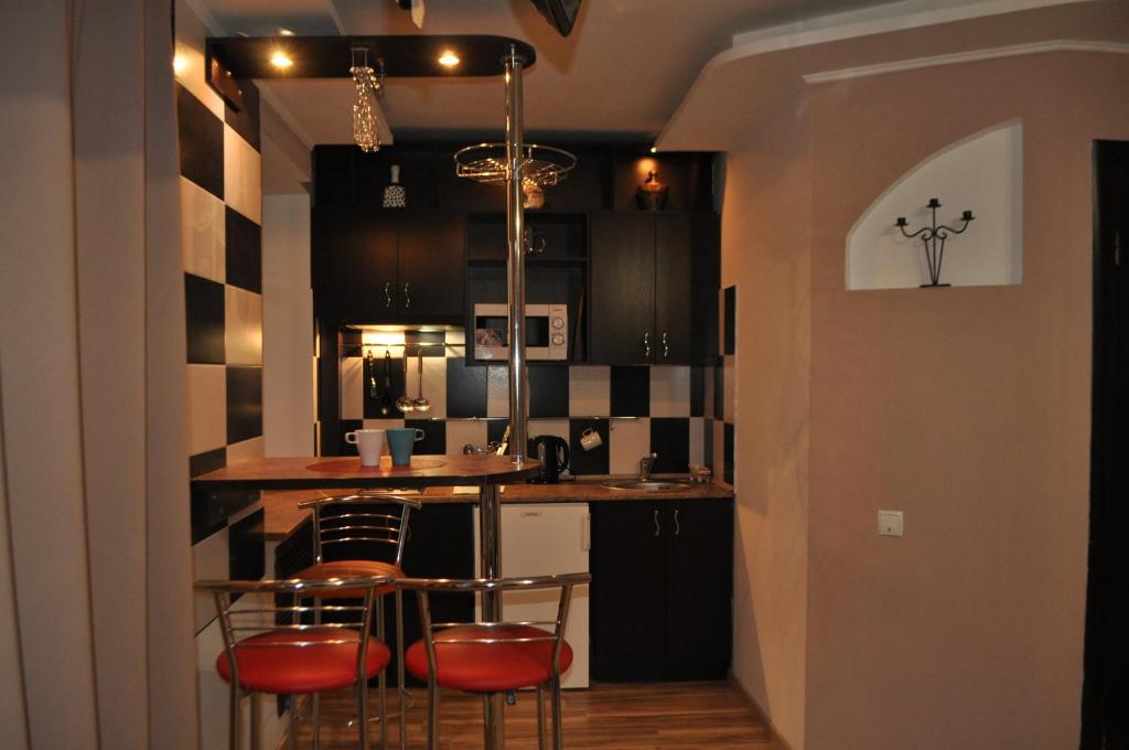 a kitchen with a bar with three chairs in it at Dwell Apartments in Kremenchuk