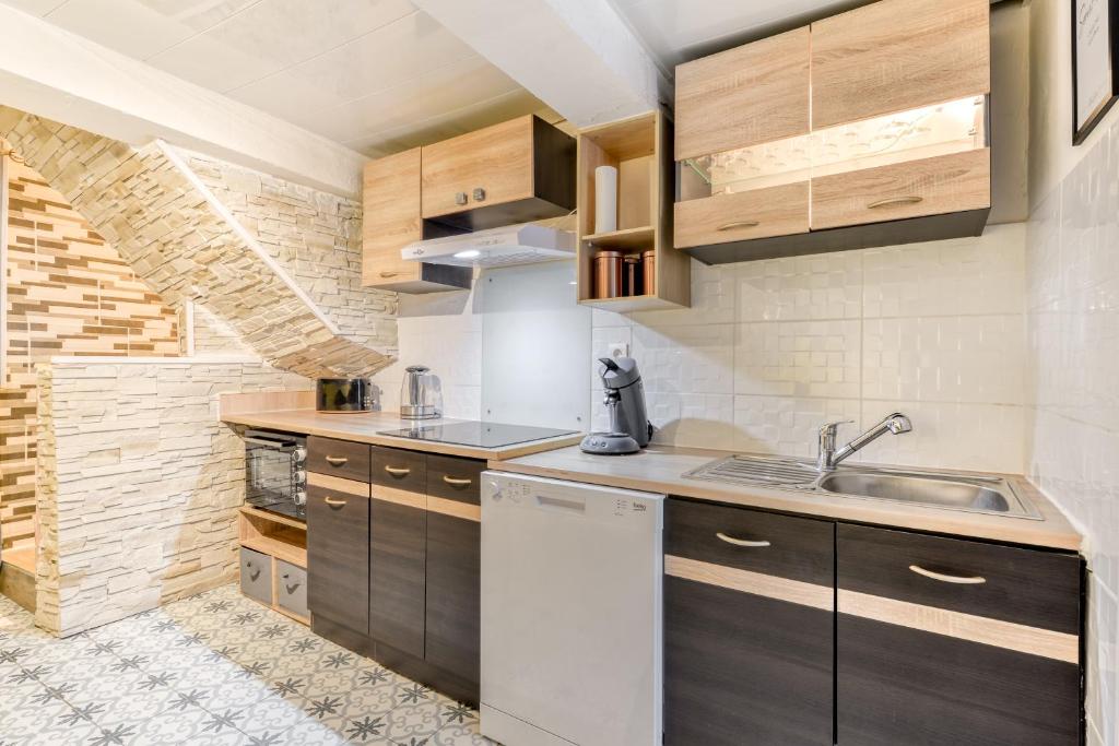 a kitchen with wooden cabinets and a sink at Le petit rubis d'Ouveillan in Ouveillan