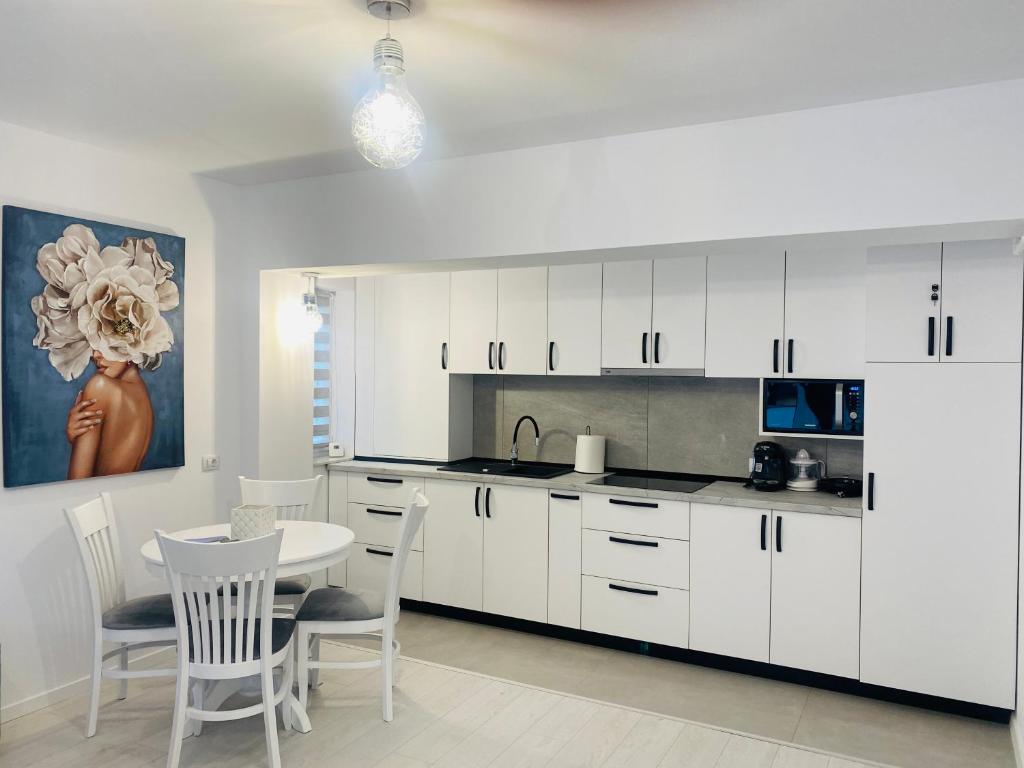 a kitchen with white cabinets and a table and chairs at Luxury Prince in Câmpulung Moldovenesc