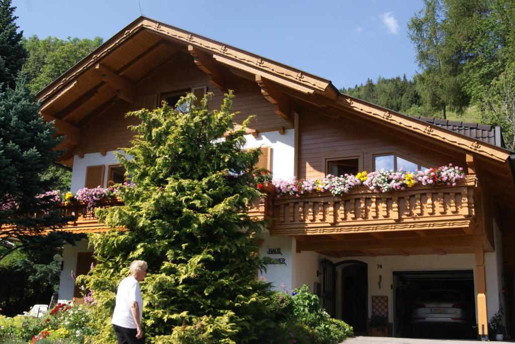 mężczyzna przechodzący przed domem z balkonem w obiekcie Gästehaus Lackner w mieście Rennweg am Katschberg