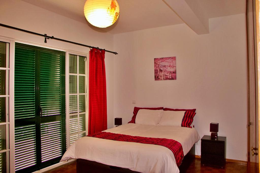 - une chambre avec un lit et une fenêtre dotée de volets verts dans l'établissement Ivone Madeira Guest House, à Funchal