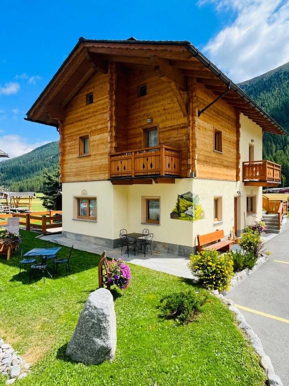 a large wooden house with a balcony on a green lawn at Chalet Sunshine in Livigno