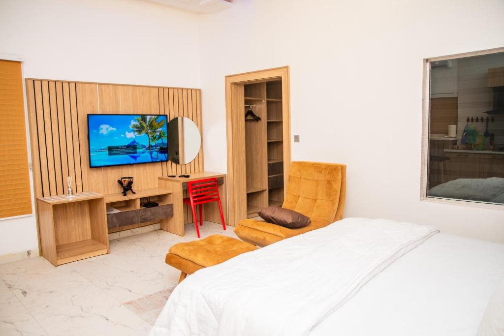 um quarto com uma cama, uma televisão e uma cadeira em Alder studio Apt+Gym+Snooker board. Rhodabode Nile em Abuja