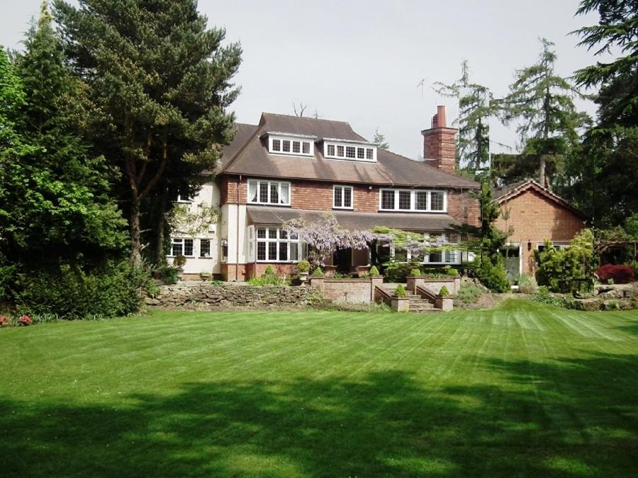 a large house with a green lawn in front of it at Coach house in Woking