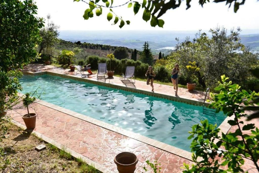 una piscina con persone che lo circondano di Villa Podere Antico con piscina a Civitella Del Lago