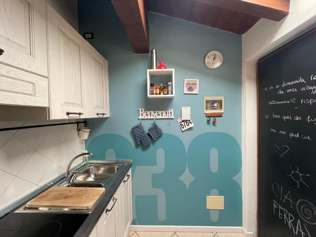eine Küche mit einem Waschbecken und einer Tafel an der Wand in der Unterkunft Mansardine Metropolitane in Brescia