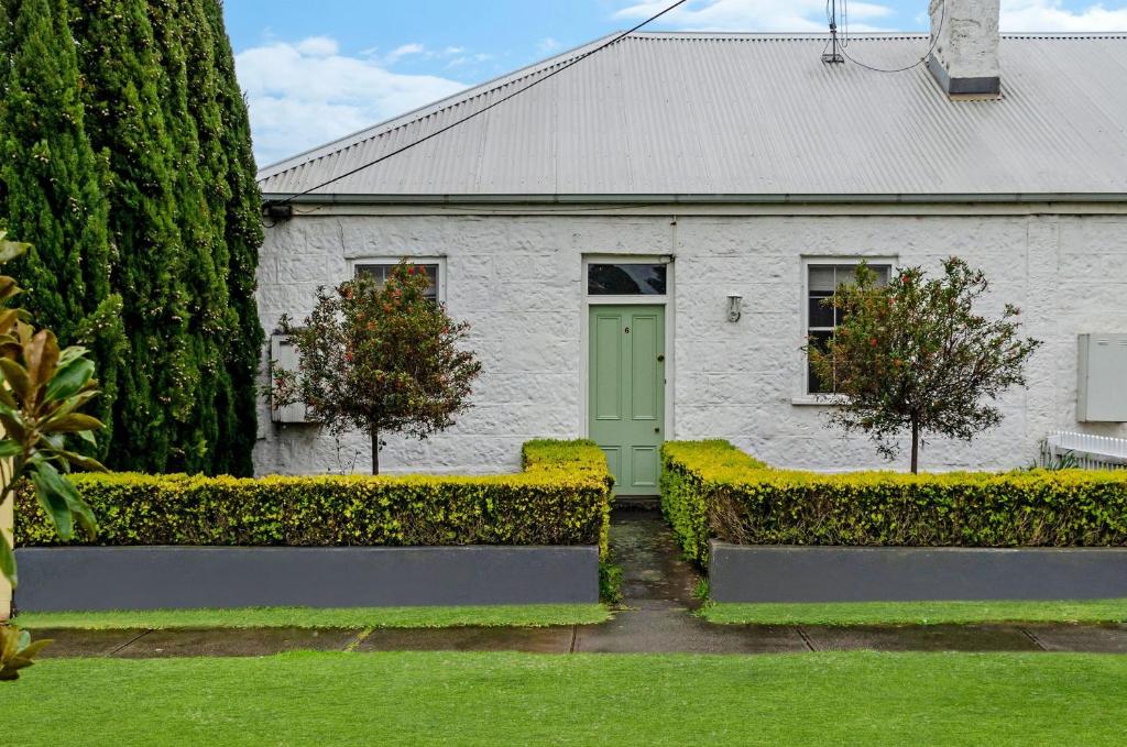 a white house with a green door in a yard at Cottage on James circa 1855 in Port Fairy