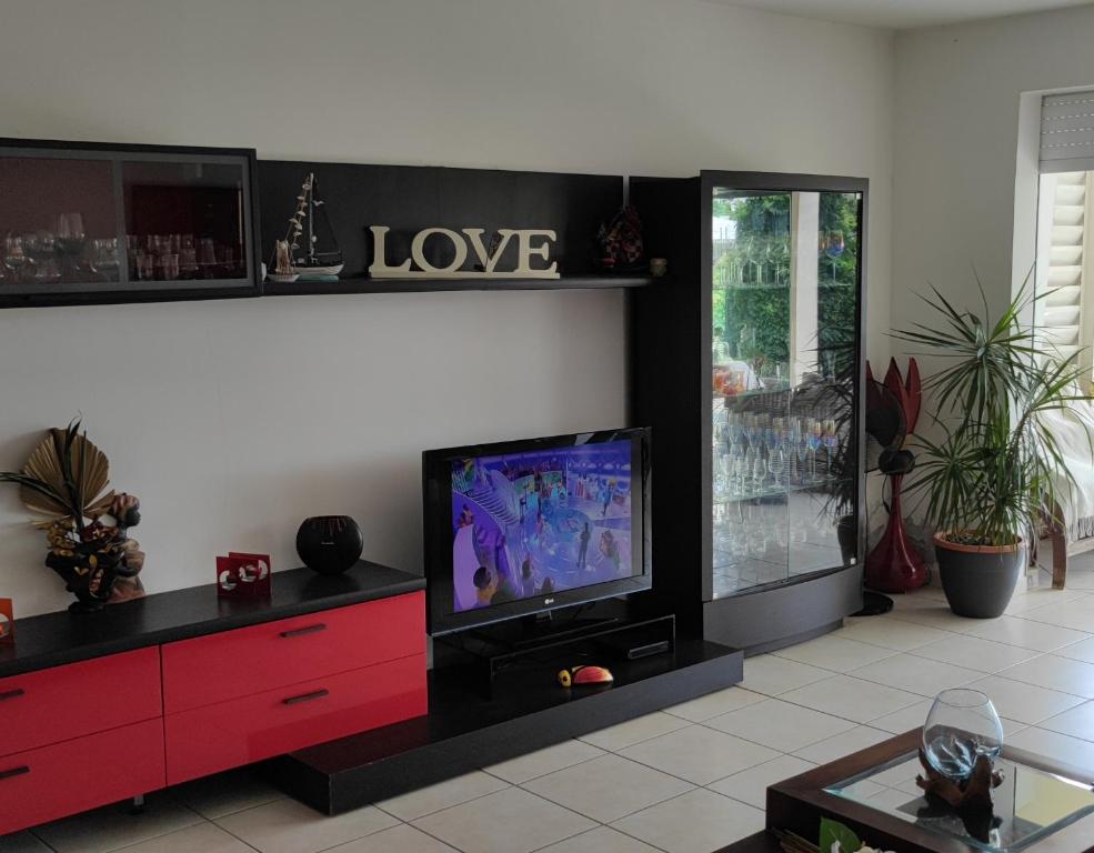 uma sala de estar com uma televisão e um armário vermelho em Chambre privée près des plus belles plages du Nord em La Trinité