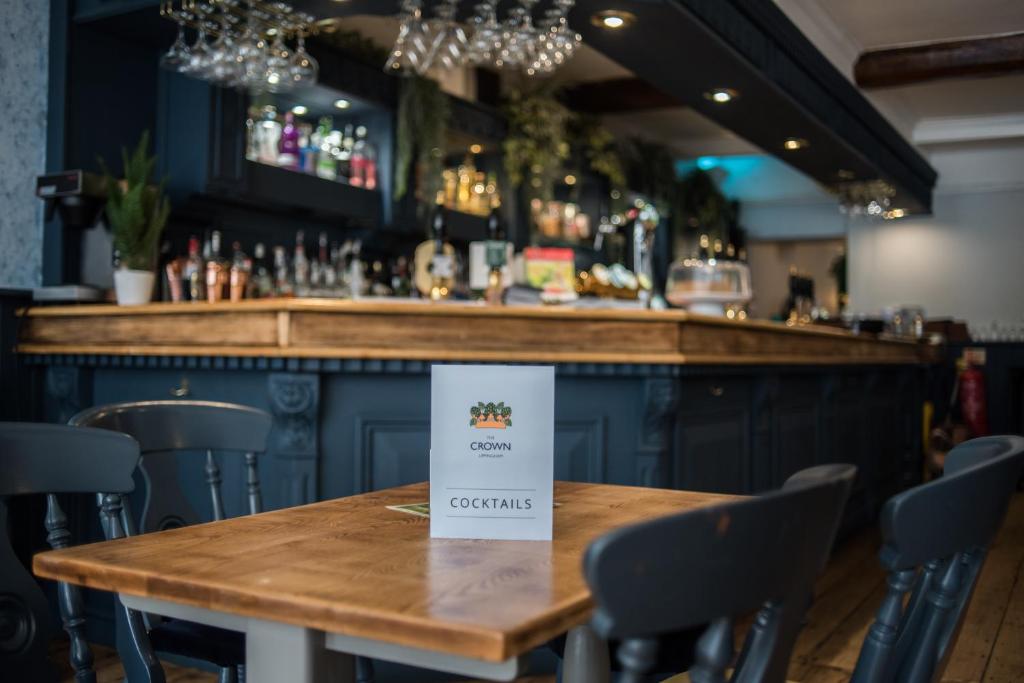 a wooden table in a bar with a sign on it at The Crown in Uppingham