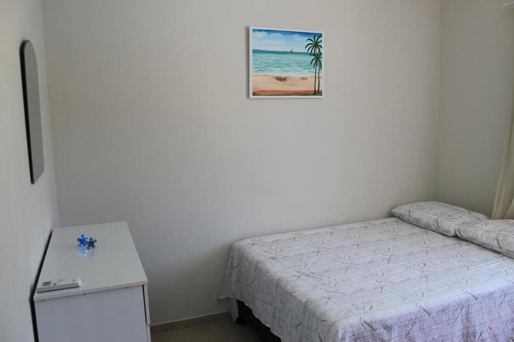 a bedroom with a bed and a picture of a beach at Gravatá beach flats in São José da Coroa Grande