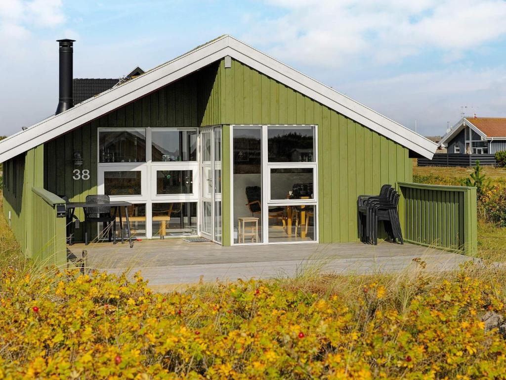 a green building with a deck in front of it at 4 person holiday home in Hvide Sande in Bjerregård