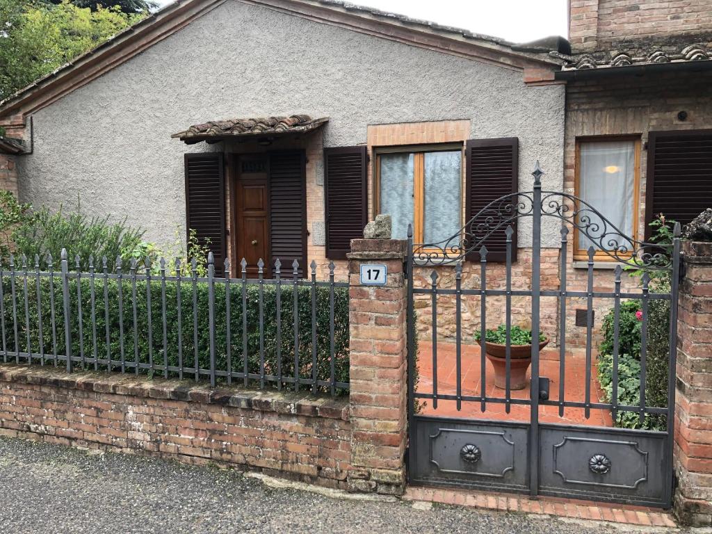 une maison en briques avec une clôture en fer noir dans l'établissement La Poderina, à Monteriggioni