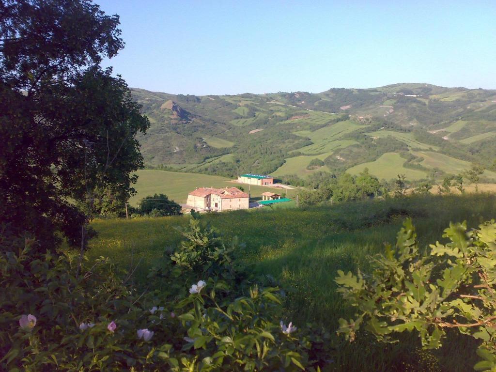 una casa in mezzo a un campo con montagne di Agriturismo Prato degli Angeli a Sassoleone