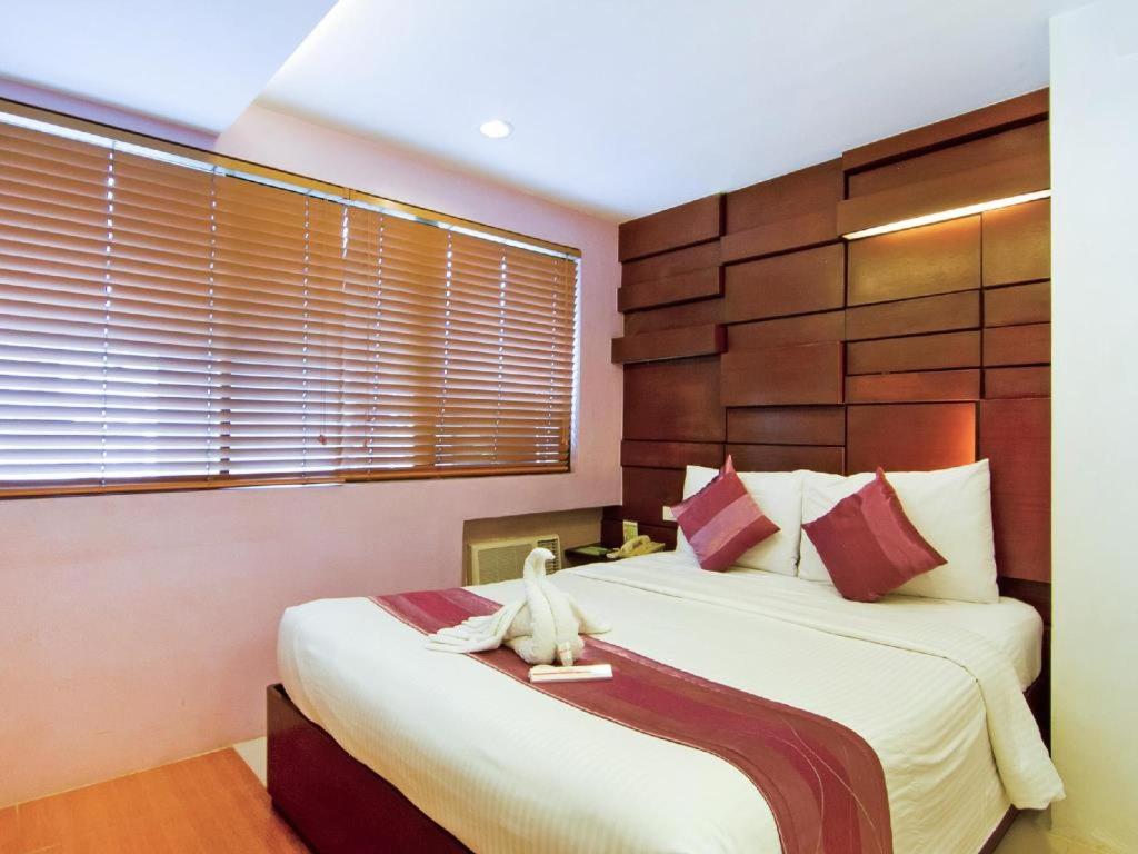 Schlafzimmer mit einem großen Bett mit einem Kopfteil aus Holz in der Unterkunft ACL Suites in Manila