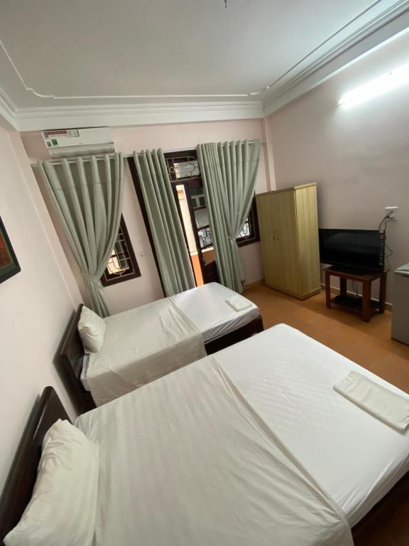 a bedroom with two beds and a chair and a desk at Hoàng Kiên Hotel in Hanoi