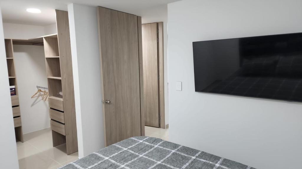 a bedroom with a bed with a flat screen tv on the wall at APARTAMENTO DE LUJO EN LA MILLA DE ORO DE IBAGUÉ, COLOMBIA. in Ibagué