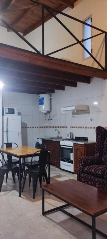 una cucina con tavolo, sedie e piano cottura di Departamentos del Campo Pehuajo, Depto tipo LOFT a Pehuajó