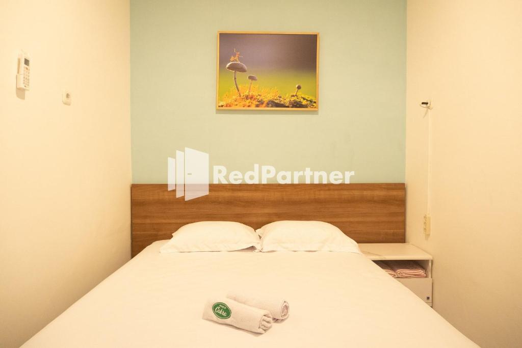 uma cama num quarto com um sinal de parceiro vermelho na parede em House Of Cokro near Malioboro Area Mitra RedDoorz em Ngabean
