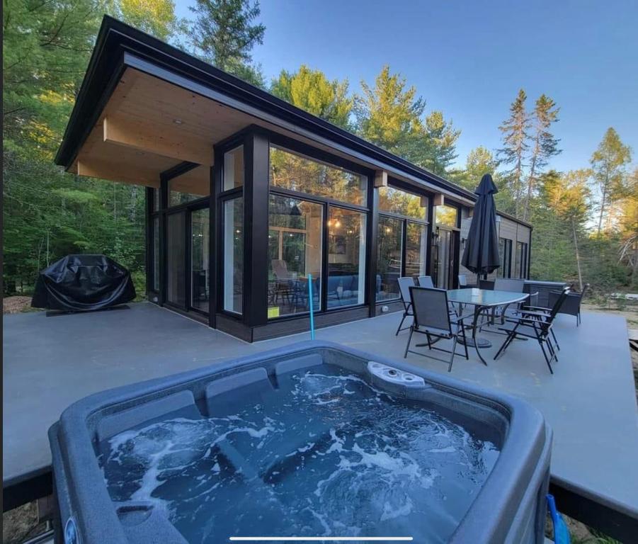 a hot tub on a patio with a table and chairs at Les Chalets Double K # 1 in Saint-Alexis-des-Monts