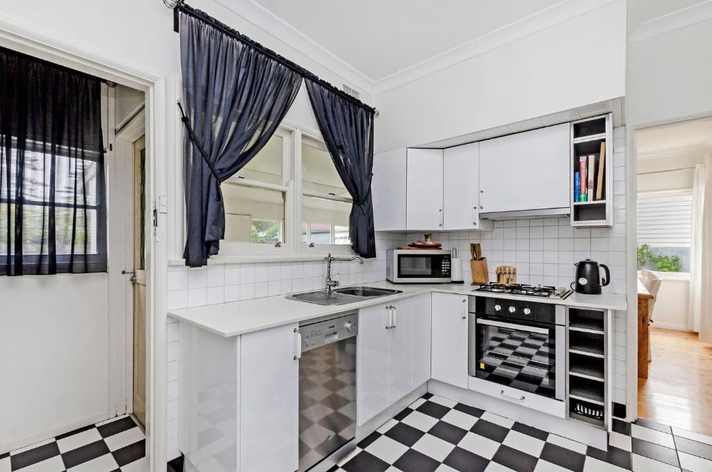 a kitchen with white appliances and a black and white checkered floor at Mary Grant in Port Fairy