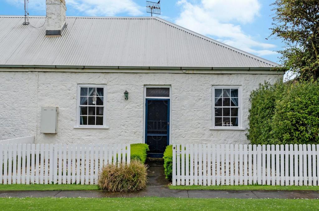 a white house with a white picket fence at Prues Cottage in Port Fairy