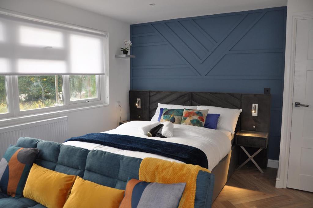 - une chambre avec un grand lit et un mur bleu dans l'établissement Luxury Studio- MK central- 5 MINS DRIVE TO TRAIN STATION-DIRECT TRAINS TO LONDON, BIRMINGHAM, à Milton Keynes