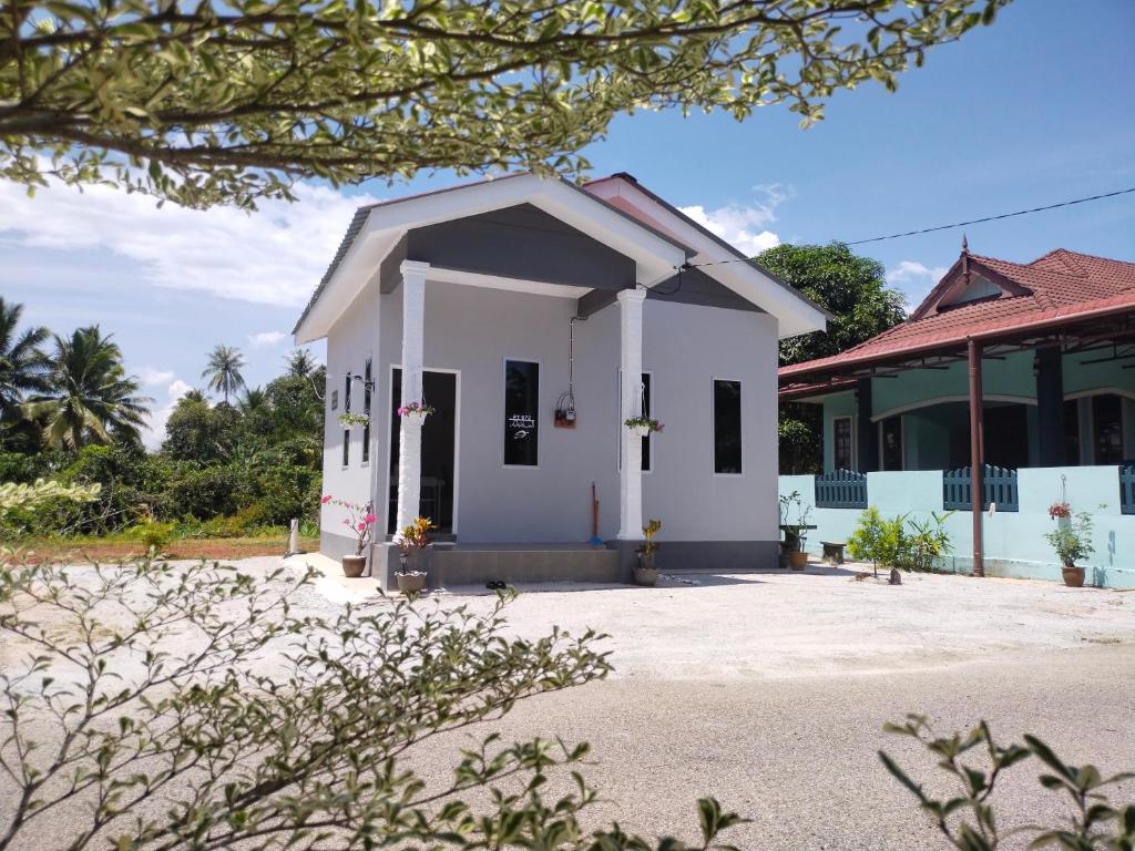 a small white building in front of a building at Wanna Homestay in Jertih