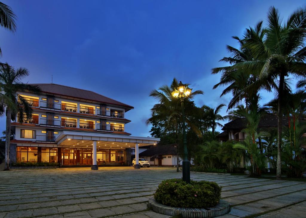 um edifício com uma palmeira em frente em Backwater Ripples Kumarakom em Kumarakom